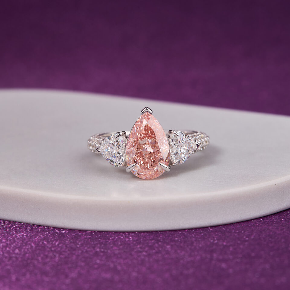 3.00 CT Fancy Pink Pear-Shaped Diamond, beautifully complemented by two heart-shaped diamonds ring